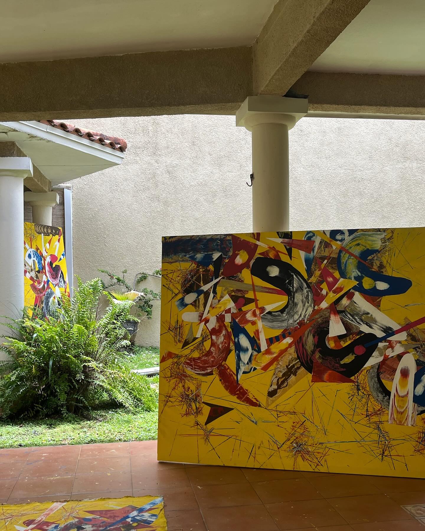 Sunlight casting shadows over a paint-splattered studio floor and canvas.