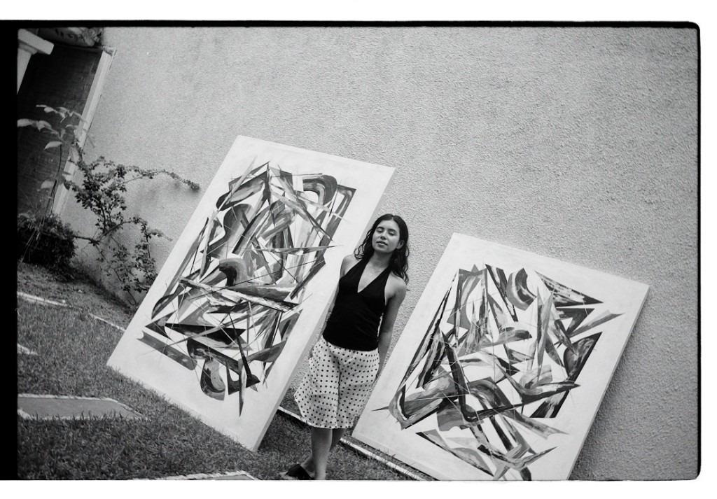 Annie Ríos standing between two paintings